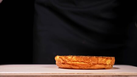 Craft burger is cooking on black background in black food gloves. Consist: red sauce salsa, lettuce, red onion, pickle, cheese, chilli green pepper, air bun and marbled meat beef. Not made ideal. Looks real, loving hand made.の写真素材