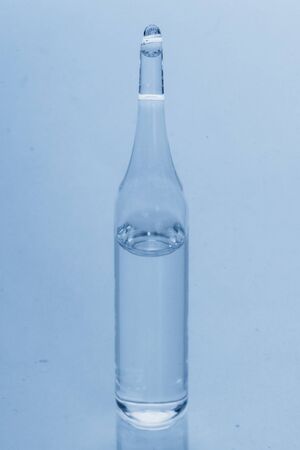 Glass medical ampoule vial for injection. Medicine is dry white drug penicillin powder or liquid with of aqueous solution in ampulla. Close up. Bottles ampule with aluminum cap on backgrounds gray.の写真素材