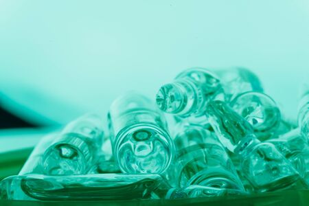 Glass medical ampoule vial for injection. Medicine is liquid sodium chloride with of aqueous solution in ampulla. Close up. Bottles ampule multicolor on background color and water. Human plasma.の写真素材