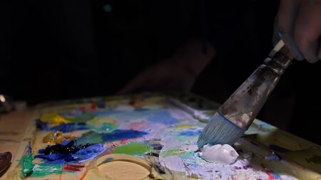 Artist copyist paint seascape with ship in ocean. Craftsman decorator draw as boat sail on blue sea with acrylic oil color. Draw finger, brush, knife palette. Indoor. Close up cinematic look.の写真素材