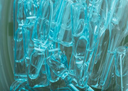 Glass medical ampoule vial for injection. Medicine is liquid sodium chloride with of aqueous solution in ampulla. Close up. Bottles ampule multicolor on background color and water. Human plasma.の写真素材