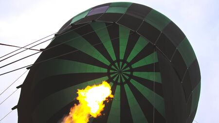 Adventure on hot air balloon watermelon. Burner directing flame into envelope. The aircraft fly in morning blue sky due to hot air. Hot air burning gas fire to air balloon or aerostat during flight.の写真素材