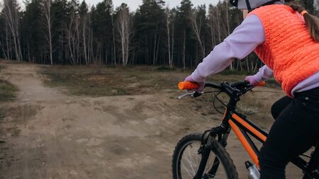 One caucasian children rides bike road track in dirt park. Girl riding black orange cycle in...