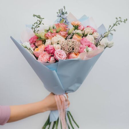 Colorful bouquet of different fresh flowers in the hands of a florist woman. Rustic flower background. Craft bouquet of flowers.の写真素材