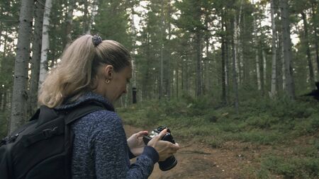 Traveler photographing scenic view in forest. One caucasian woman shooting nice magic look. Girl...