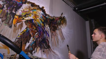 Artist designer draws an eagle on the wall. Craftsman decorator paints a picture with acrylic oil...