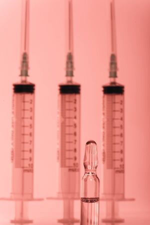 Glass medical ampoule vial for injection. Medicine is liquid sodium chloride with of aqueous solution in ampulla. Close up. Bottles ampule multicolor on background color and water. Human plasma.の写真素材