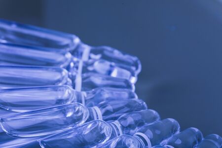 Glass medical ampoule vial for injection. Medicine is liquid sodium chloride with of aqueous solution in ampulla. Close up. Bottles ampule multicolor on background color and water. Human plasma.の写真素材