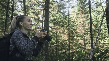 Traveler photographing scenic view in forest. One caucasian woman shooting nice magic look. Girl...