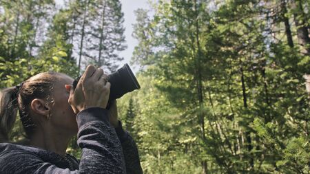 Traveler photographing scenic view in forest. One caucasian woman shooting nice magic look. Girl take photo video on dslr mirrorless camera. Professional photographer travel with backpack. Outdoor.の写真素材