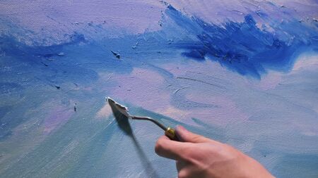 Artist copyist paint seascape with ship in ocean. Craftsman decorator draw as boat sail on blue sea with acrylic oil color. Draw finger, brush, knife palette. Indoor. Close up cinematic look.の写真素材