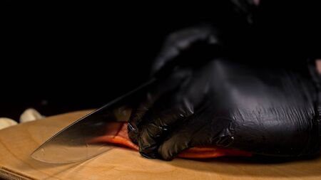 The cook makes salsa. Salsa for burgers on hot Mexican hot recipes. It is prepared from a tomato, red chili peppers, onions, white onions. All chalks are cut with a knife.の写真素材