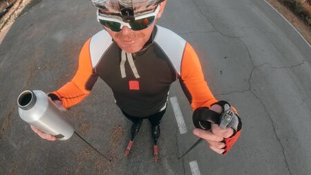 Training an athlete on the roller skaters. Pov view action cam. Biathlon ride on the roller skis with ski poles, in the helmet. Autumn workout. Roller sport. Adult man riding on skates.の写真素材