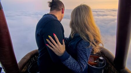 Adventure love couple on hot air balloon watermelon. Man and woman kiss hug love each other. Burner directing flame into envelope. Fly in morning blue sky. Happy people take selfie in hot air ballon.の写真素材