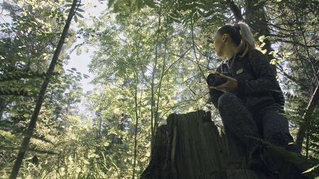 Traveler photographing scenic view in forest. One caucasian woman shooting nice magic look. Girl take photo video on dslr mirrorless camera. Professional photographer travel with backpack. Outdoor.の写真素材