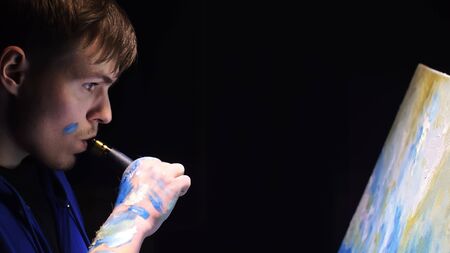 Artist copyist paint seascape with ship in ocean. Vaper smoke vape e-cigarette. Craftsman decorator draw as boat sail on blue sea with acrylic oil color. Draw finger, brush, knife palette. Indoor.の写真素材