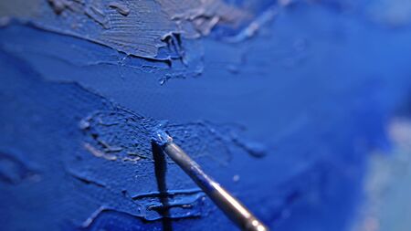 Artist copyist paint seascape with ship in ocean. Craftsman decorator draw as boat sail on blue sea with acrylic oil color. Draw finger, brush, knife palette. Indoor. Close up cinematic look.の写真素材