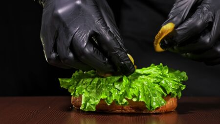 Craft burger is cooking on black background. Consist: red sauce salsa, lettuce, red onion, pickle, cheese, chilli green pepper, air bun and marbled meat beef. Not made ideal. Loving hand made.の写真素材