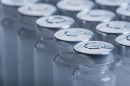 Glass medical ampoule vial for injection. Medicine is dry white drug penicillin powder or liquid with of aqueous solution in ampulla. Close up. Bottles ampule with aluminum cap on backgrounds gray.の写真素材