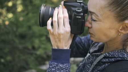Traveler photographing scenic view in forest. One caucasian woman shooting close up look. Girl take...