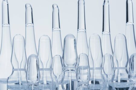 Glass medical ampoule vial for injection. Medicine is dry white drug penicillin powder or liquid with of aqueous solution in ampulla. Close up. Bottles ampule with aluminum cap on backgrounds gray.の写真素材