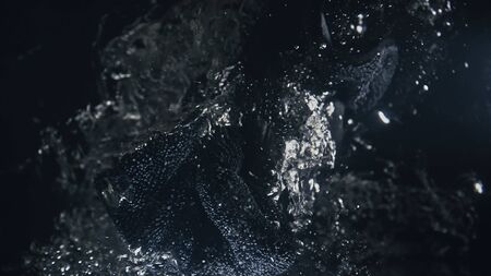 A professional dry microfiber rag for washing a car is dipped in water. Bottom view from under the water. Underwater view of towel in hand in black glove. The tissue in fluid air bubbles and flows.の写真素材