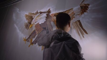 Artist designer draws an eagle on wall. Craftsman decorator paints picture with acrylic oil color...
