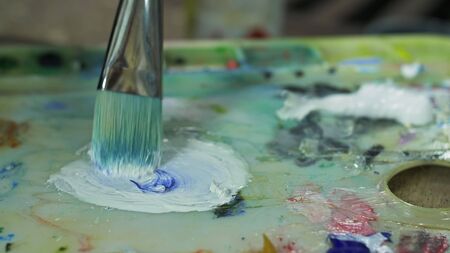 Artist copyist paint seascape with ship in ocean. Craftsman decorator draw as boat sail on blue sea with acrylic oil color. Draw finger, brush, knife palette. Indoor. Close up cinematic look.の写真素材