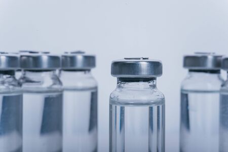 Glass medical ampoule vial for injection. Medicine is dry white drug penicillin powder or liquid with of aqueous solution in ampulla. Close up. Bottles ampule with aluminum cap on backgrounds gray.の写真素材
