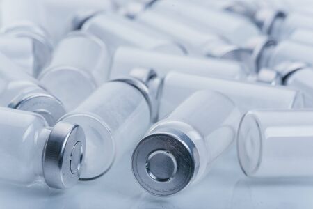 Glass medical ampoule vial for injection. Medicine is dry white drug penicillin powder or liquid with of aqueous solution in ampulla. Close up. Bottles ampule with aluminum cap on backgrounds gray.の写真素材