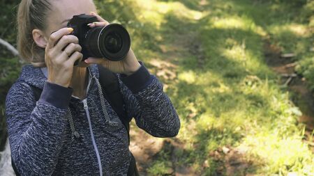 Traveler photographing scenic view in forest. One caucasian woman shooting close up look. Girl take...