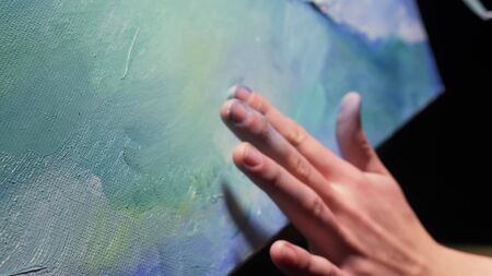 Artist copyist paint seascape with ship in ocean. Craftsman decorator draw as boat sail on blue sea with acrylic oil color. Draw finger, brush, knife palette. Indoor. Close up cinematic look.の写真素材