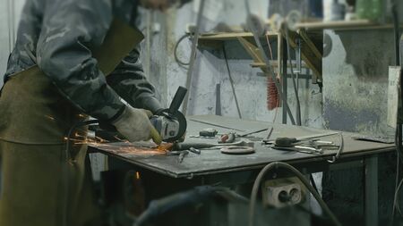 Forge workshop on table. Smithy manual production. Work on the product. Ruler, angle grinder. The blacksmith makes iron products for manufacture of fireplaces, stoves.の写真素材