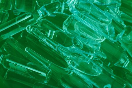 Glass medical ampoule vial for injection. Medicine is liquid sodium chloride with of aqueous solution in ampulla. Close up. Bottles ampule multicolor on background color and water. Human plasma.の写真素材