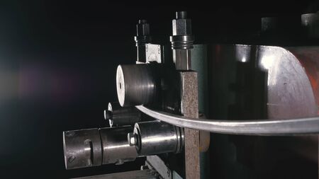 Forge workshop on table. Smithy manual production. Worker bends the metal rod on the wrought iron round bending machine. Manufacturing of a designer part from a metal rod. The blacksmith manufacture.の写真素材