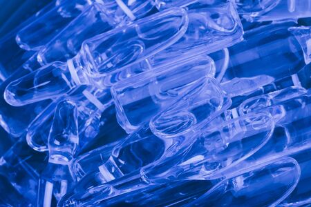 Glass medical ampoule vial for injection. Medicine is liquid sodium chloride with of aqueous solution in ampulla. Close up. Bottles ampule multicolor on background color and water. Human plasma.の写真素材