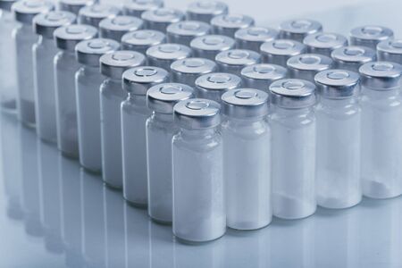 Glass medical ampoule vial for injection. Medicine is dry white drug penicillin powder or liquid with of aqueous solution in ampulla. Close up. Bottles ampule with aluminum cap on backgrounds gray.の写真素材