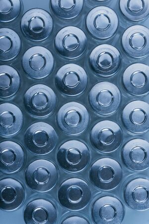 Glass medical ampoule vial for injection. Medicine is dry white drug penicillin powder or liquid with of aqueous solution in ampulla. Close up. Bottles ampule with aluminum cap on backgrounds gray.の写真素材