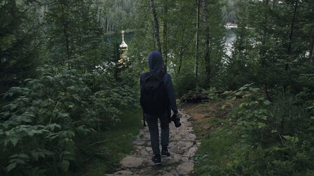 Traveler photographing scenic view in forest. One caucasian woman shooting nice magic look. Girl take photo video on dslr mirrorless camera. Professional photographer travel with backpack. Outdoor.の写真素材