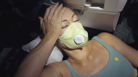 Woman travel caucasian at plane with wearing protective medical mask. Girl tourist at aircraft with...
