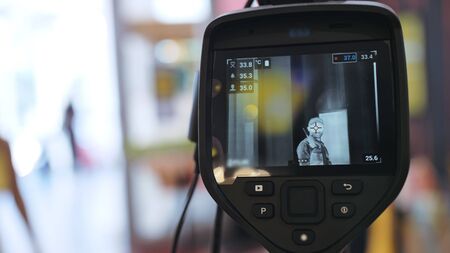 Temperature check at a supermarket, grocery store with a thermal imaging camera installed. Image monitoring scanner to monitor the body temperature of visitor customer. Coronavirus pandemic outbreak.の写真素材