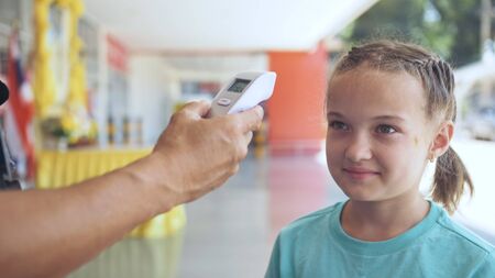 Temperature check at a supermarket of little girl, grocery store with thermal imaging camera...