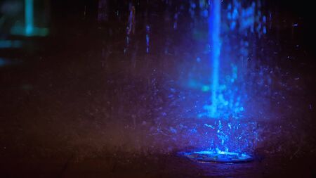 Splashes of fountain. Water illuminated in colorful falling on fountain which change it water color in night. Wonderful multicolored fountain throws up high streams of sparkling water.の写真素材