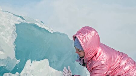 Girl walking on cracked ice of frozen lake Baikal. Woman traveler explores and looks at an ice floe....