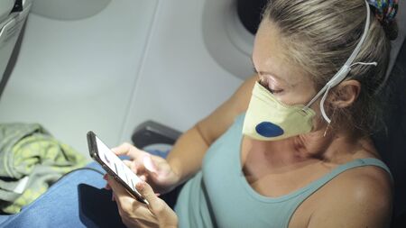 Woman travel tourist caucasian at plane aircraft with wearing protective medical mask. Read shock...