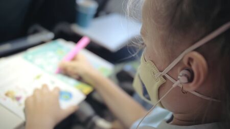 Little girl caucasian at plane with wearing protective medical mask. Child baby tourist at aircraft...