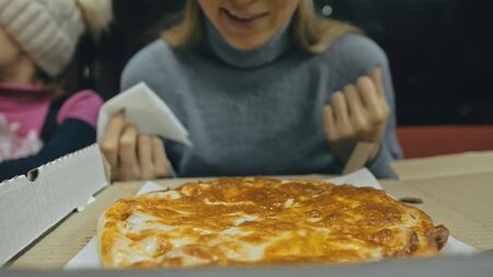 Girl eat pizza cheese four. Close up of young woman mouth greedily eating pizza and chewing in outdoor restaurant. Human hands taking pieces slices of hot tasty italian pizza from open box. Junk food.の写真素材