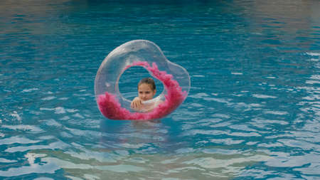 The little cute girl have fun in the swim pool. The child enjoy summer vacation in a swimming pool...