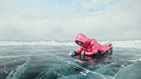 Girl walking on cracked ice of frozen lake Baikal. Woman traveler explores and looks at an ice floe....