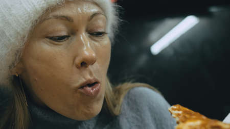 Girl eat pizza cheese four. Close up of young woman mouth greedily eating pizza and chewing in outdoor restaurant. Human hands taking pieces slices of hot tasty italian pizza from open box. Junk food.の写真素材